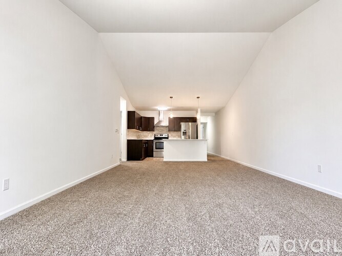 A spacious living room with a kitchen in the background.