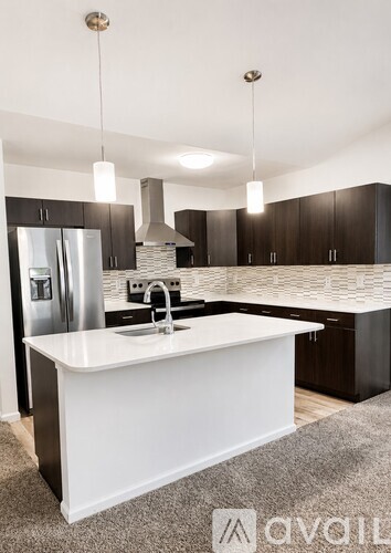 A modern kitchen with a white island and dark wood cabinets.