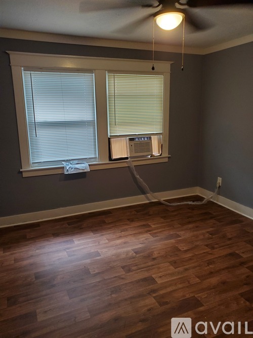 A room with wooden flooring and a window with blinds.