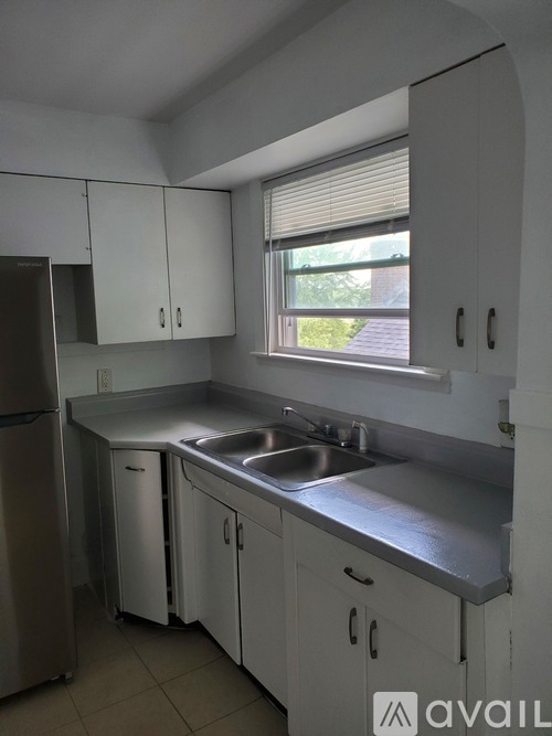 A kitchen with white cabinets and a stainless steel refrigerator.