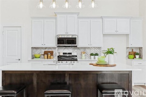 A kitchen with white cabinets and a dark counter.