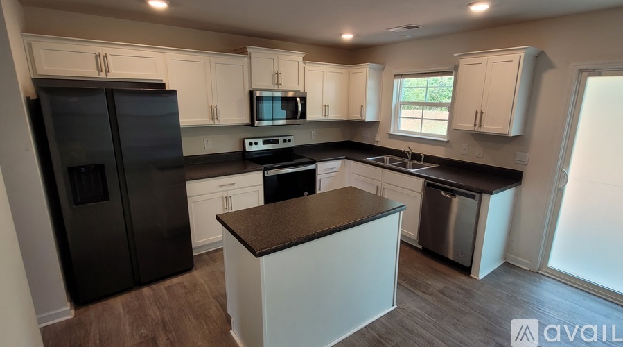 A kitchen with black appliances and white cabinets.