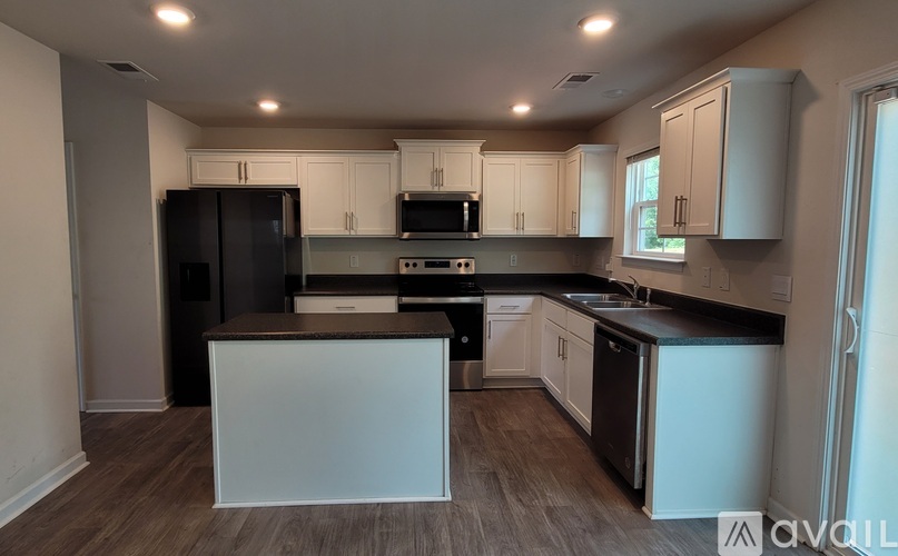 A kitchen with black appliances and white cabinets.