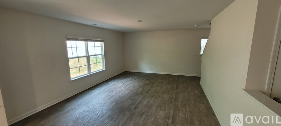 A spacious room with wooden flooring and a large window.