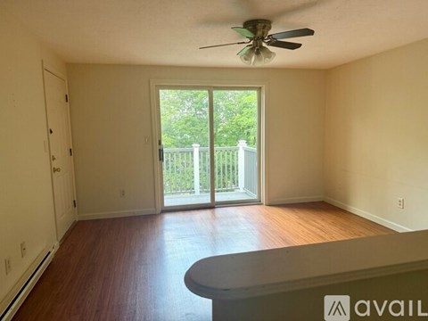 A room with a ceiling fan and sliding glass doors leading to a balcony.