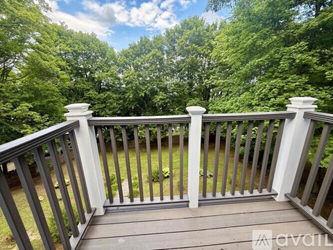 A deck with a railing and a view of a green forest.
