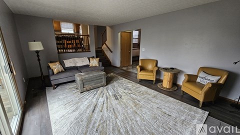 A living room with a grey rug and two yellow chairs.