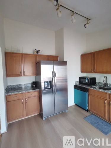 A kitchen with wooden cabinets and a stainless steel refrigerator.