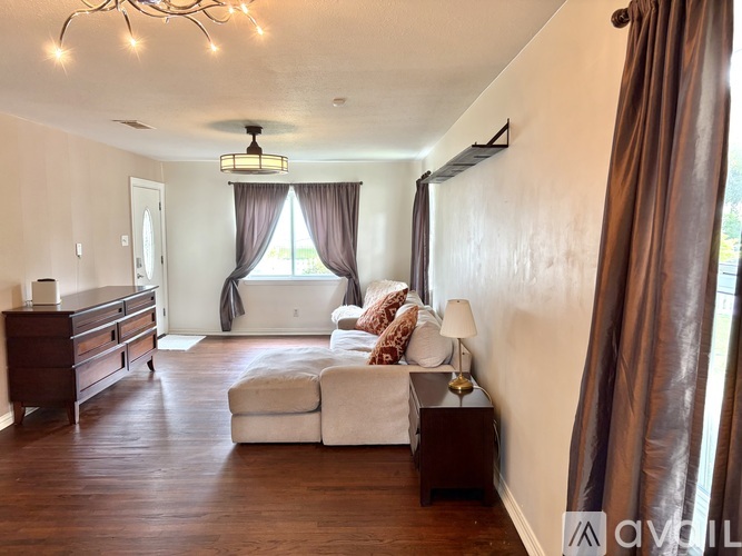 A living room with a white couch and brown curtains.