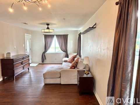 A living room with a white couch and brown curtains.