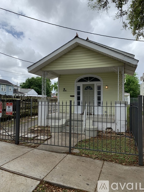 A small yellow house with a black fence in front.