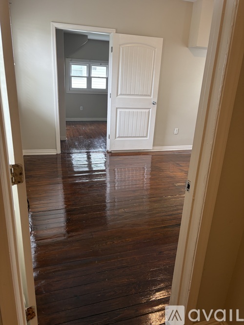 A room with a white door and wooden floors.
