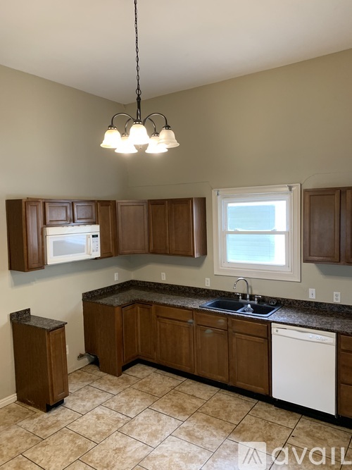 A kitchen with brown cabinets and a white dishwasher.