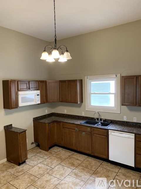 A kitchen with brown cabinets and a white dishwasher.