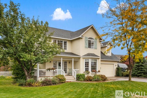 A house with a front porch and a tree with yellow leaves.