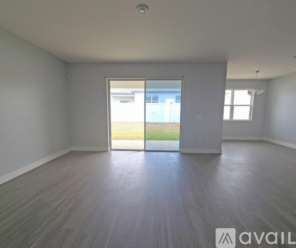 A spacious room with a large window and a sliding glass door leading to a balcony.