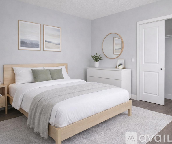 A bedroom with a large bed, a nightstand with a plant, and two framed pictures on the wall.