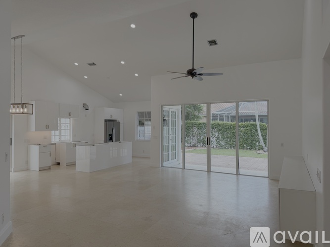 A spacious, empty room with a ceiling fan and a large window.