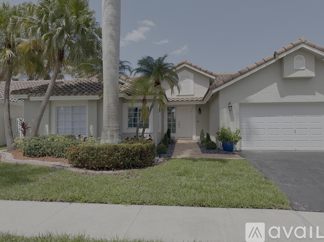 A house with a driveway and palm trees in front.
