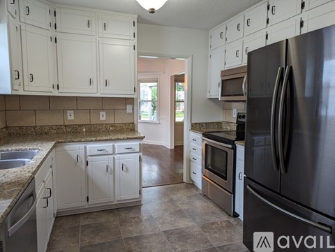 A kitchen with white cabinets and a black refrigerator.