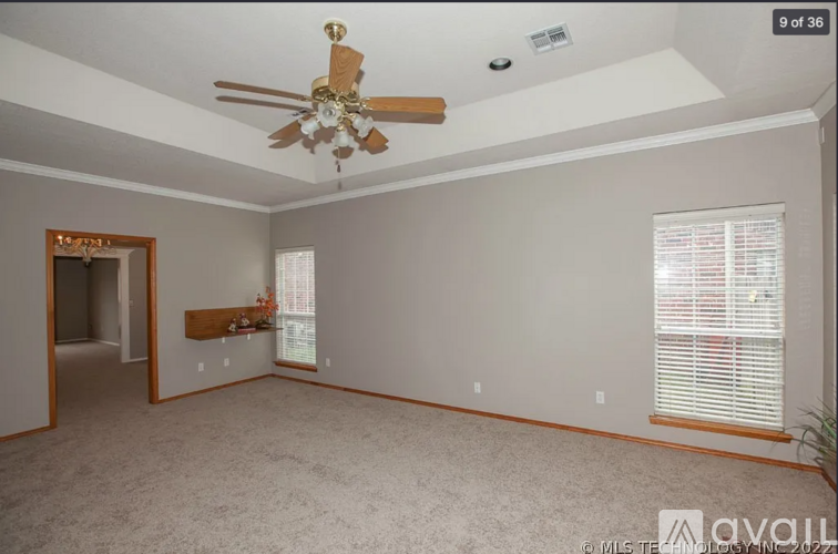 A spacious room with a ceiling fan and a window with blinds.