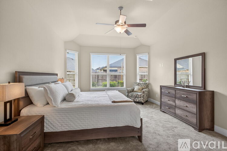 A bedroom with a large bed, a chair, and a dresser.