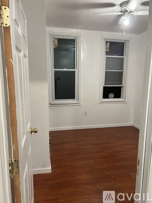 A room with a ceiling fan and two windows.