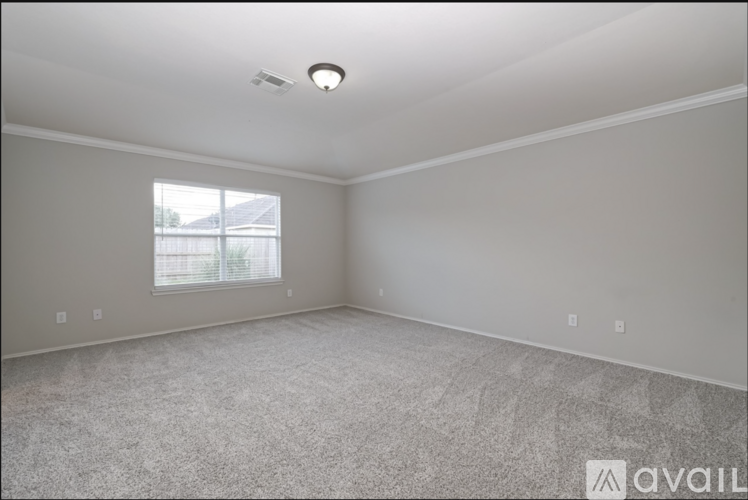 A spacious room with a window and carpeted floor.