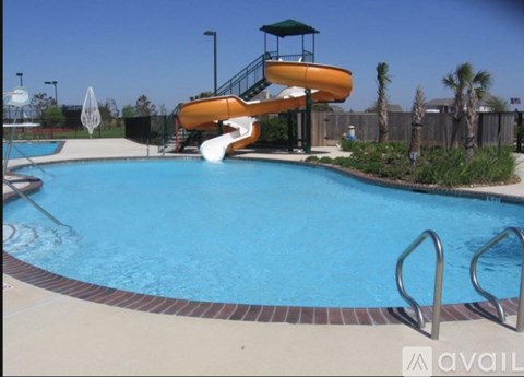 A pool with a slide and a lifeguard tower.