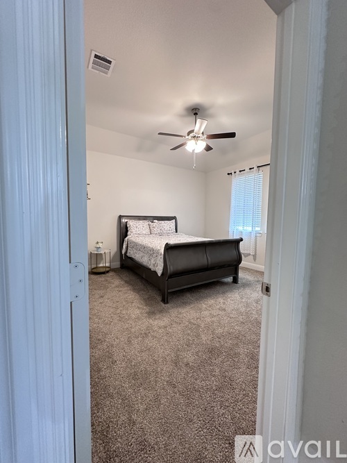 A bedroom with a bed, carpet, and a ceiling fan.