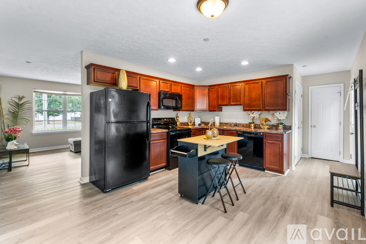 A kitchen with wooden cabinets and a black refrigerator.