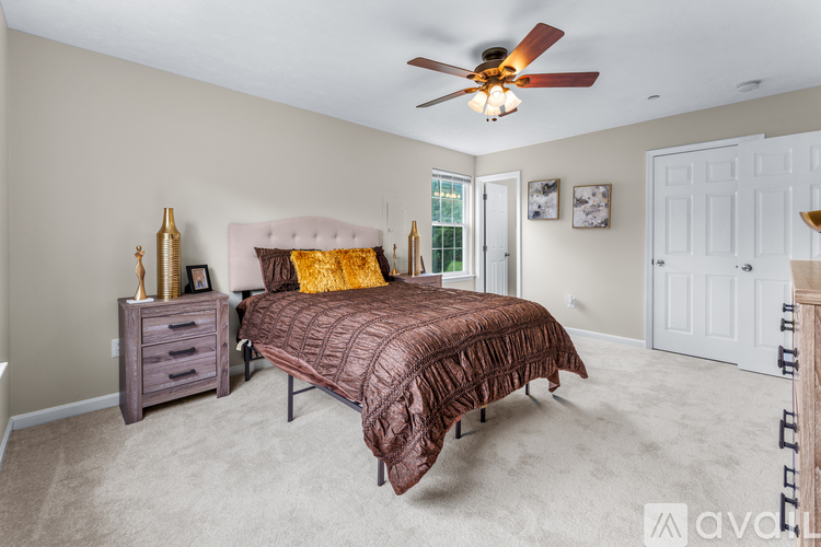 A bedroom with a bed, nightstand, and a ceiling fan.
