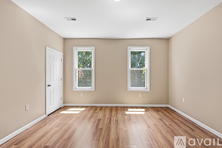 A room with wooden floors and two windows.