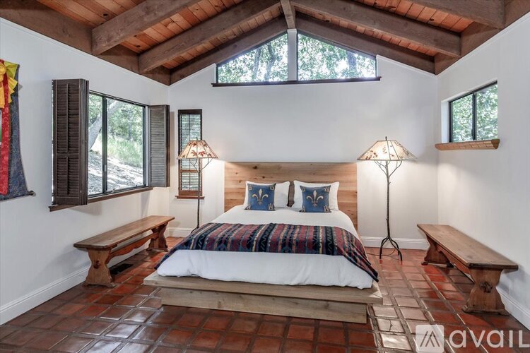 A bedroom with a bed in the middle and two lamps on the sides.