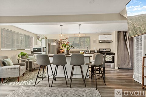 A modern kitchen with a dining table set up with four grey chairs.