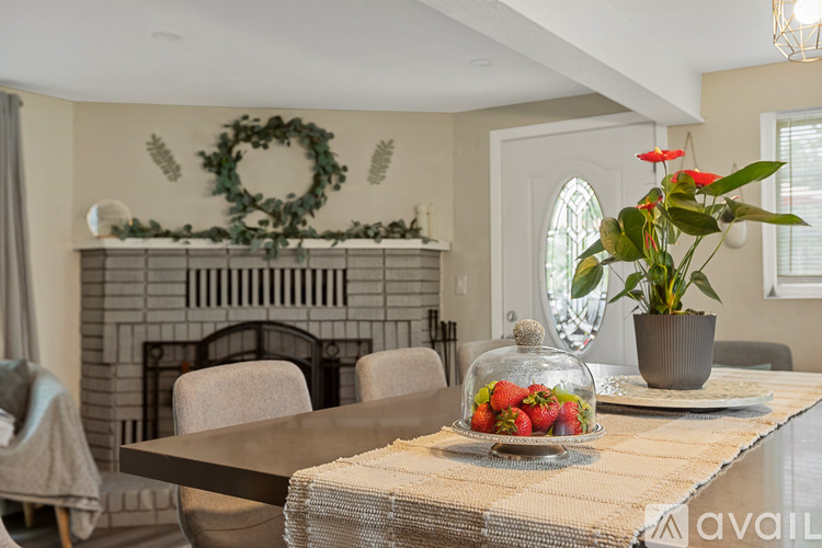 A dining room with a table set for strawberries and a wreath on the wall.