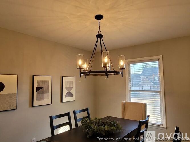 A dining room with a table, chairs, and a chandelier.