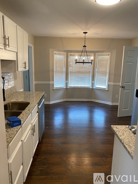 A kitchen with white cabinets and a granite countertop.