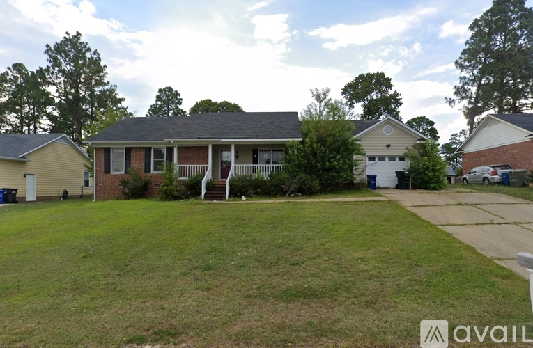 A house with a front yard and a tree in the background.