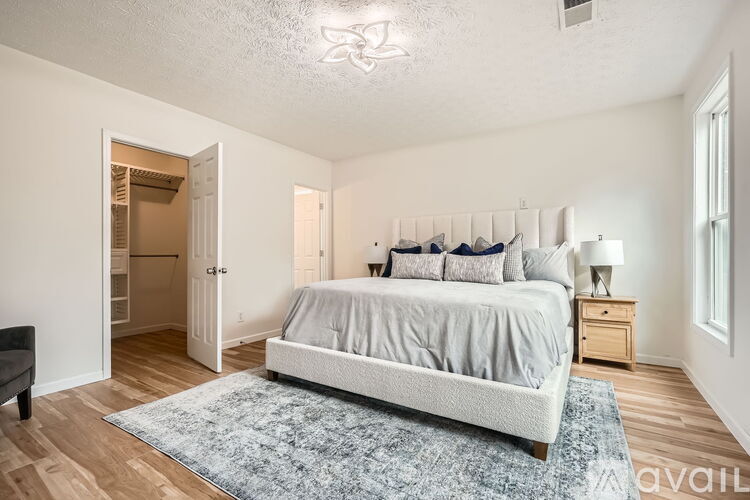 A bedroom with a bed, nightstand, and a rug.