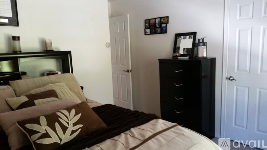 A bedroom with a bed, nightstand, and a wall with pictures.