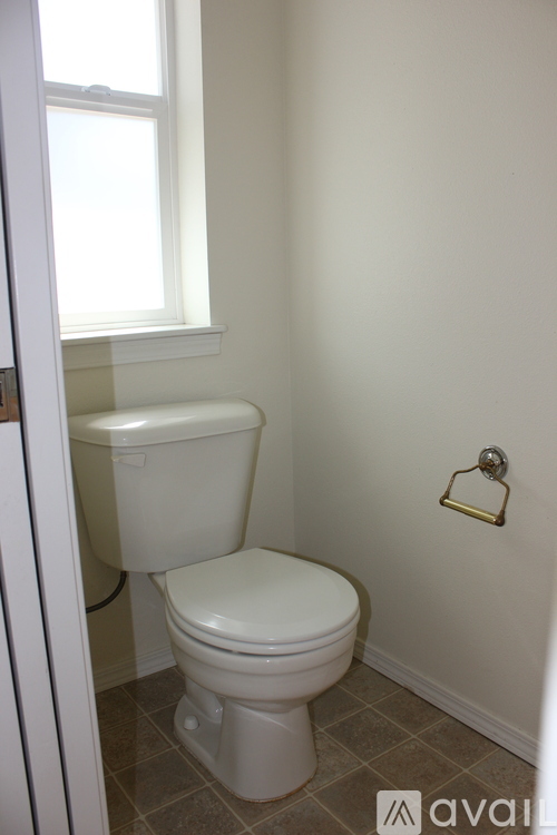 A white toilet in a small bathroom with a window.