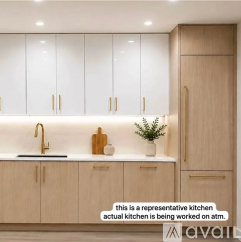 A kitchen with wooden cabinets and a note that the actual kitchen is being worked on.