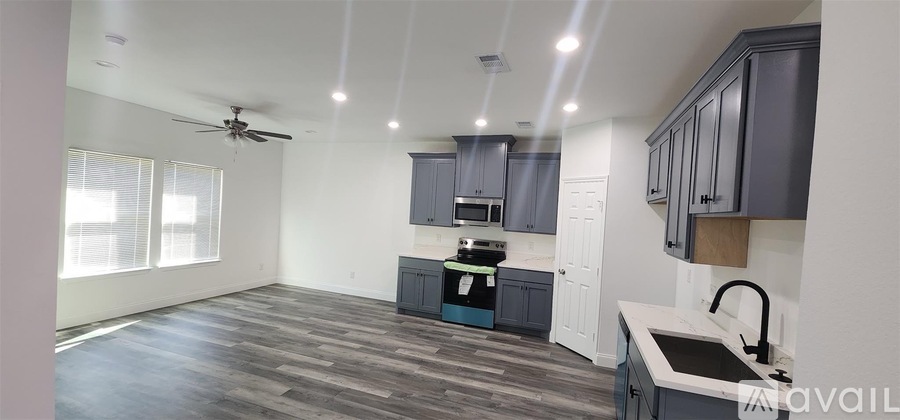 A spacious kitchen with dark wood flooring and a ceiling fan.
