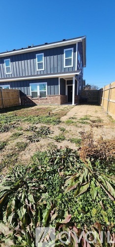 A house with a blue and white exterior and a brown fence.