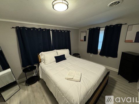 A bedroom with a white bed and black curtains.