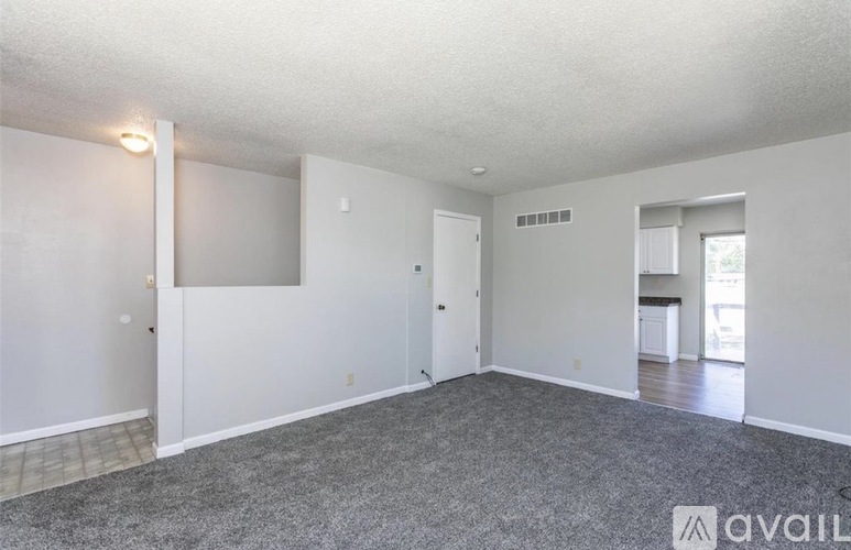 A spacious room with a grey carpet and white walls.
