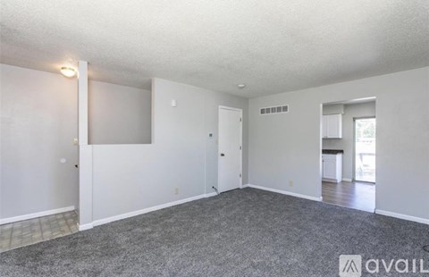 A spacious room with a grey carpet and white walls.
