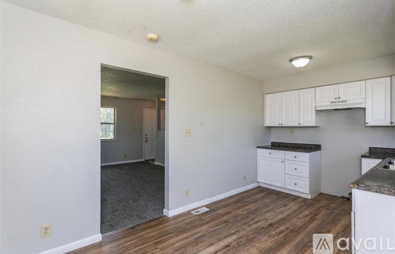 A kitchen with white cabinets and a wooden floor.