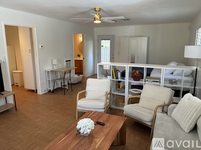 A living room with a white couch, a wooden coffee table, and a ceiling fan.